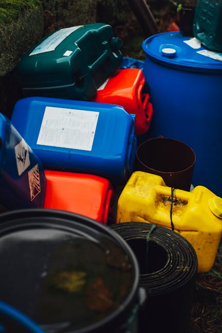 A close-up view of a large pile of crushed aluminum cans and empty soft drink cans, primarily in silver, with some featuring visible branding such as a red Coca-Cola can. The cans show various texture